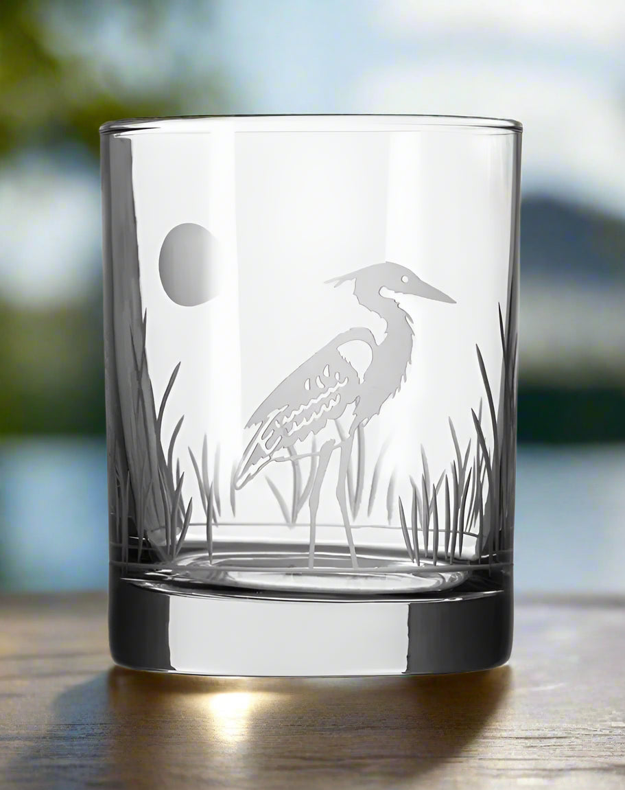 Clear glass tumbler with heron etching on a white background