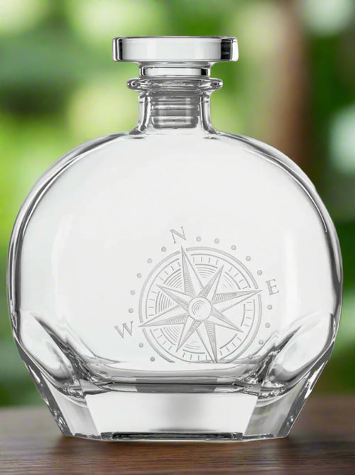 Clear glass decanter with compass engraving on a white background